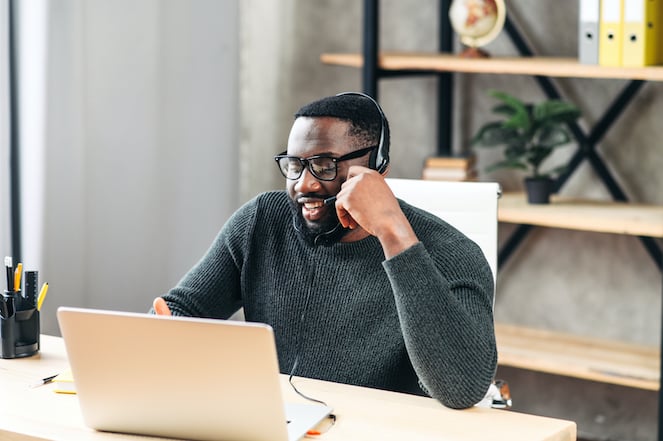 African-American guy with headset using a laptop to make a sale.