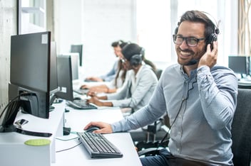 Employee working on computer smiling with earphones